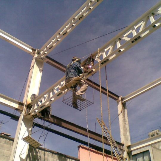 Trabajador soldando estructura metálica en alturas MMS Arquitectos