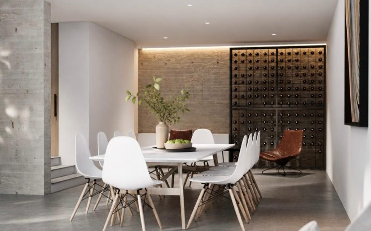 Comedor moderno de doble altura con mesa blanca, sillas, muro de ladrillo, cava de vinos iluminada y concreto aparente. Diseño por MMS Arquitectos en Estado de México y Ciudad de México