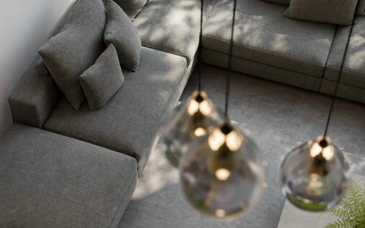 Sala moderna con sillón seccional gris, lámparas colgantes esféricas de cristal y mesa de centro. Diseño de interiores por MMS Arquitectos en Estado de México y Ciudad de México