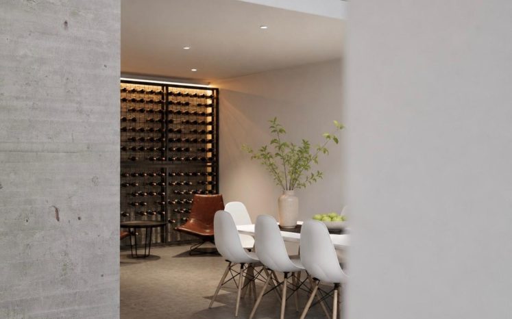 Comedor minimalista con cava de vinos iluminada al fondo, mesa blanca con sillas y muro de concreto. Diseño por MMS Arquitectos en Estado de México y Ciudad de México