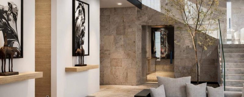 Sala minimalista a doble altura con escalera, árbol interior, lámpara colgante y sofás grises. Diseño interior por MMS Arquitectos en Estado de México y Ciudad de México