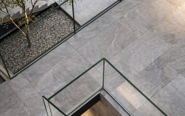 Vista aérea de patio interior con escaleras de piedra, árbol y barandal de cristal. Diseño arquitectónico por MMS Arquitectos en Estado de México y Ciudad de México